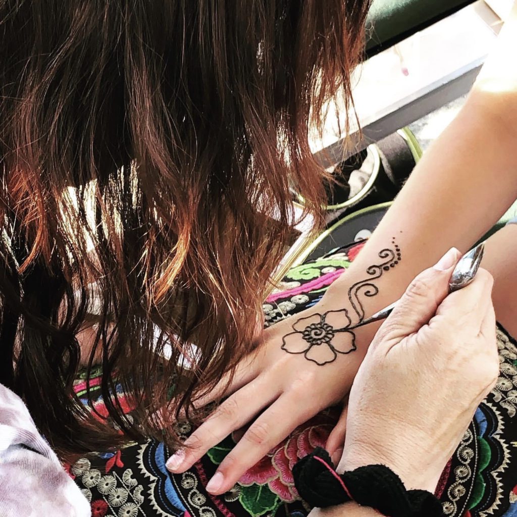 Amy Wilde draws a henna flower on a clients hand.