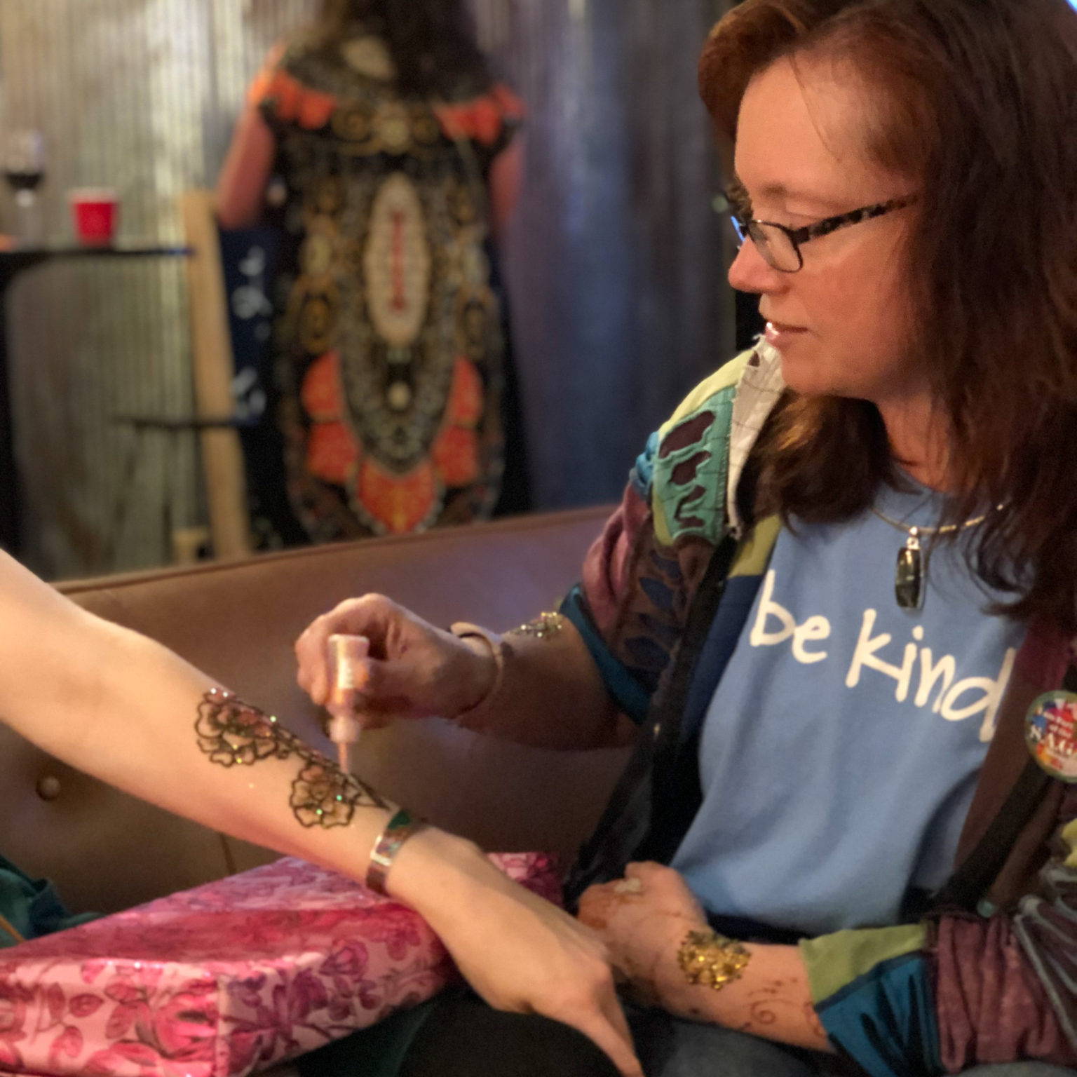 Amy puts glitter on a henna design