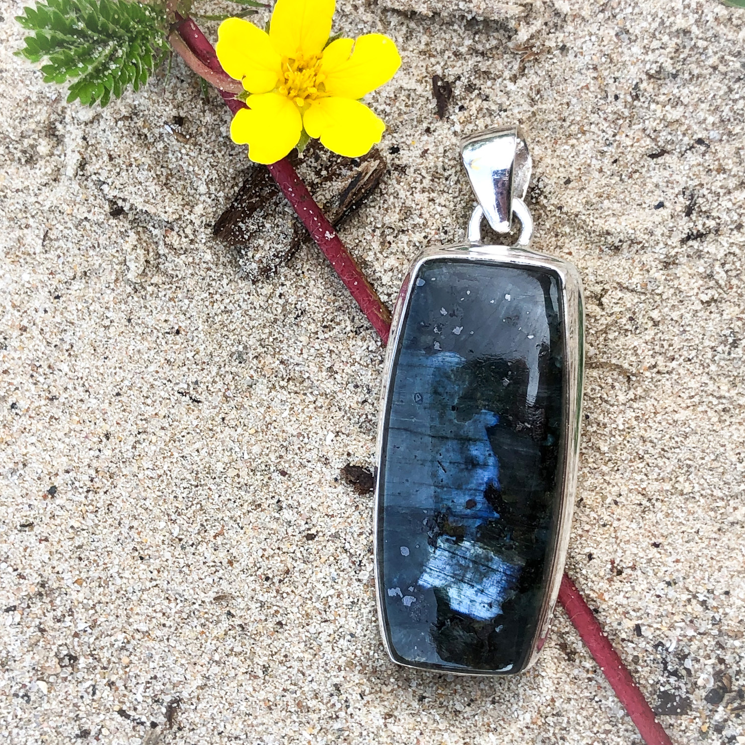 Labradorite pendant on a sandy beach