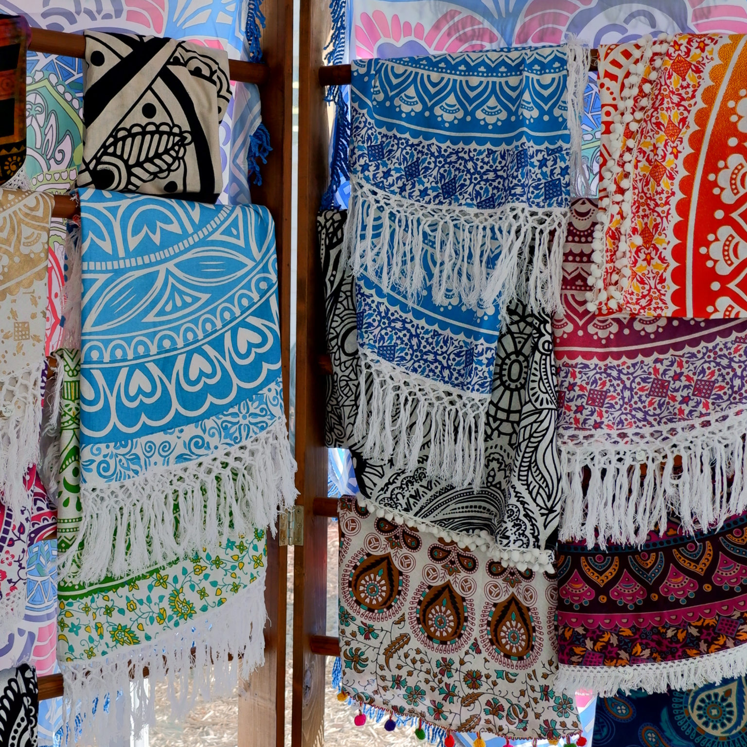 a variety of colorful round tapestries displayed on a rack